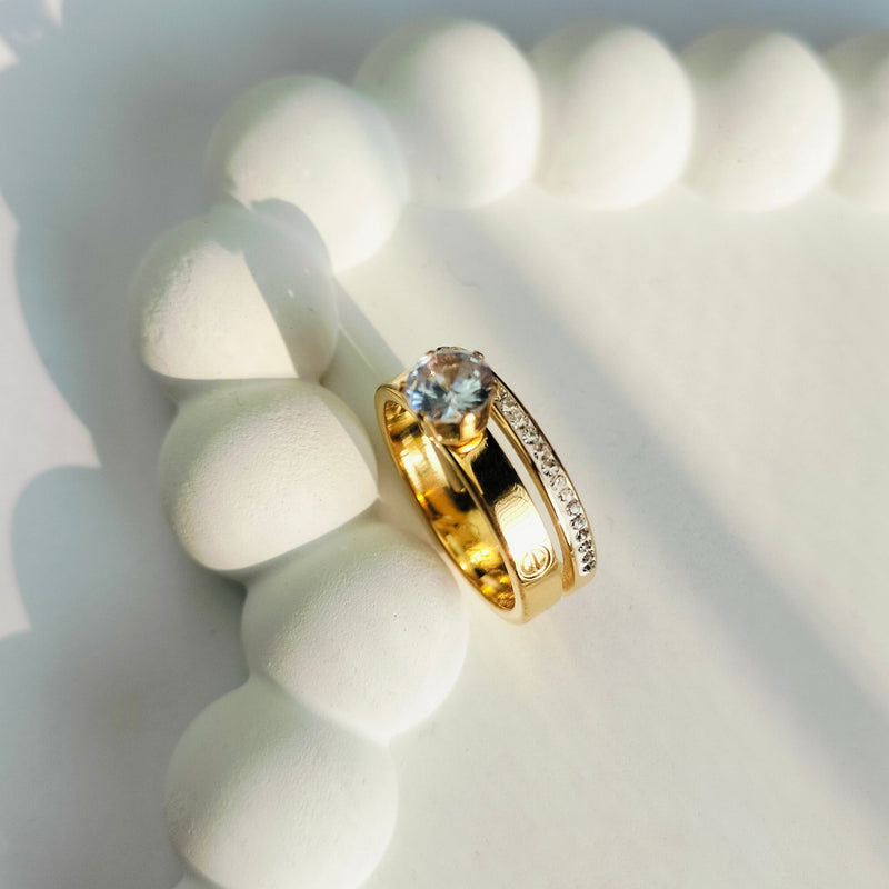 Gold ring with a blue gemstone on a white textured surface